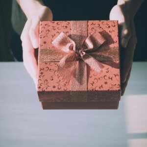 Hands presenting a beautifully wrapped gift box with a floral pattern, perfect for any celebration.